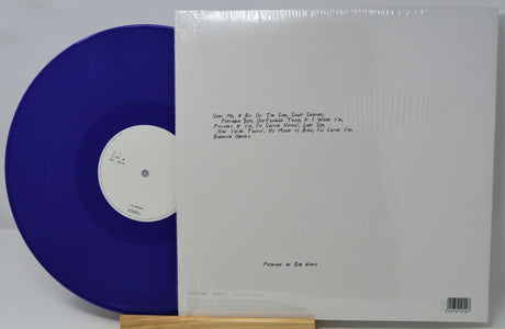 Blue vinyl record with white label and white sleeve on a gray background