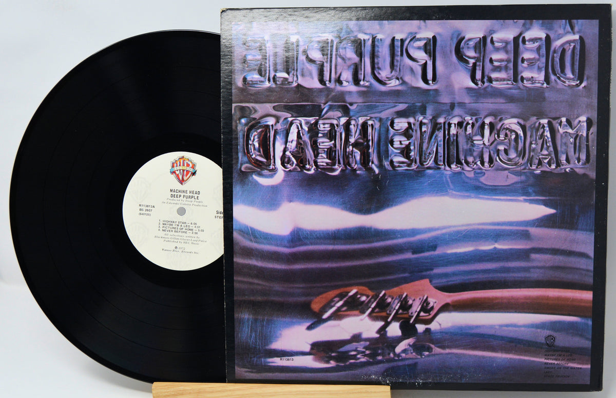 A vinyl record and its album cover for Deep Purple's 'Machine Head' displayed on a small wooden stand against a white background.
