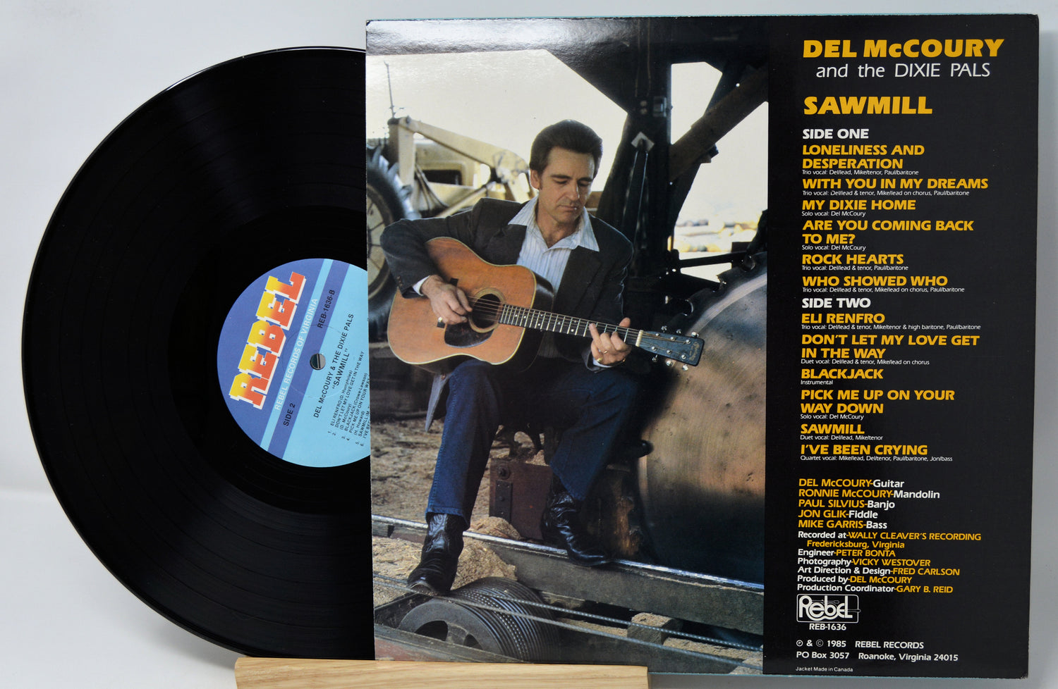 Del McCoury and the Dixie Pals 'Sawmill' vinyl record with the black LP partially visible behind the album cover, photographed on a light neutral background.