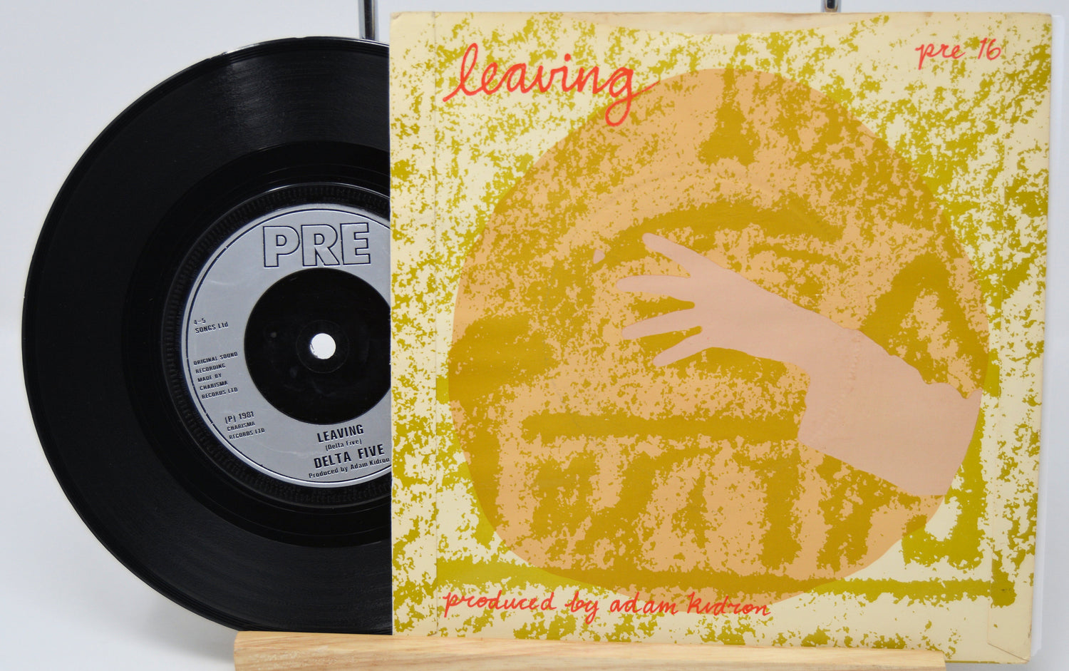 Vinyl record and cover with a hand reaching towards a face on a yellow background