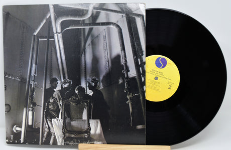 Vinyl record with a black and white album cover showing a group of people in a room.