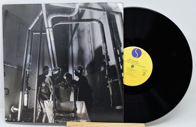 Vinyl record with a black and white album cover showing a group of people in a room.