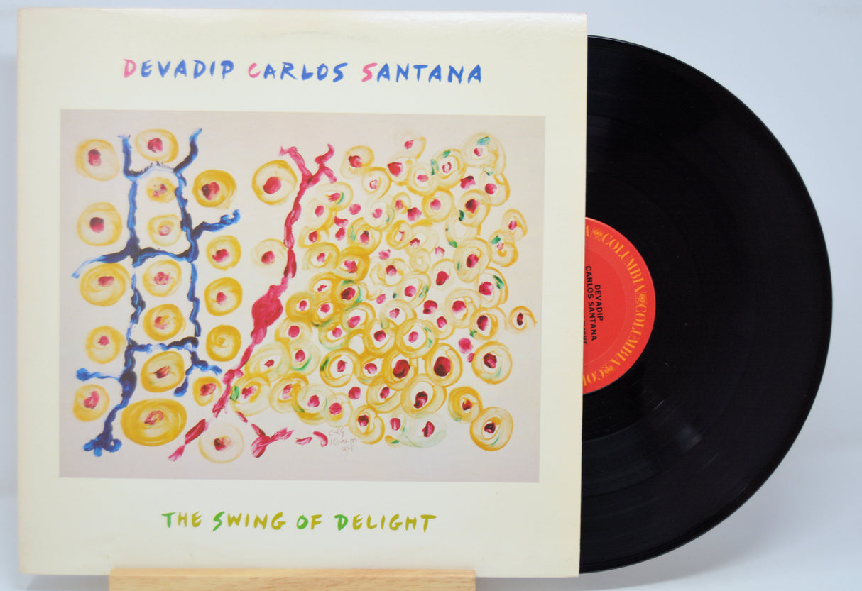 'Devadip Carlos Santana The Swing Of Delight' Vinyl record with a colorful cover featuring abstract designs and text.
