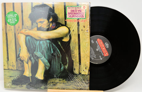 Vinyl record with cover featuring a person sitting against a wooden fence.