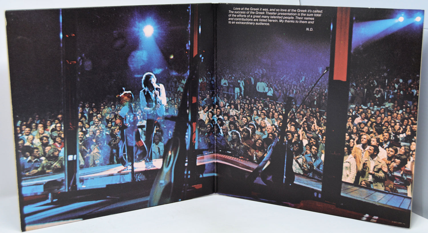 Open book showing a concert scene with a performer on stage and a large audience.