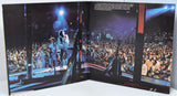 Open book showing a concert scene with a performer on stage and a large audience.