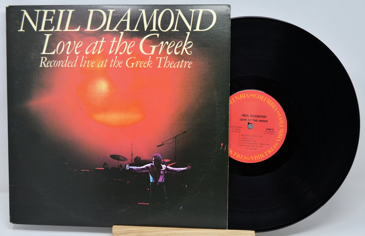 Vinyl record and cover of 'Love at the Greek' by Neil Diamond on a white background