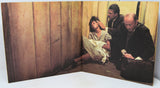 Book or magazine with a scene of a woman being comforted by two men against a wooden paneled wall.
