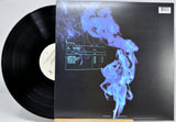 Vinyl record album shown with the black LP partially pulled from the sleeve, which features a dark cover with a glowing blue smoke-like graphic and tracklist text.