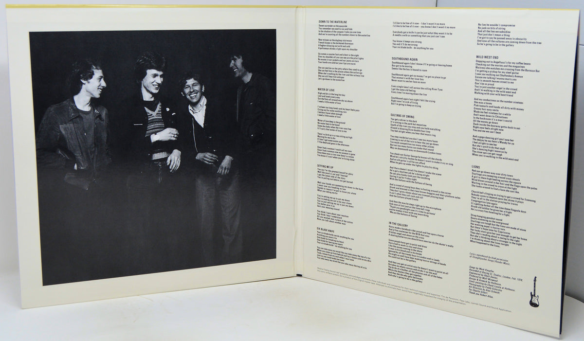 An open printed book or album booklet photographed from above on a white surface. The left page shows a black-and-white photograph of four people standing together, and the right page contains multiple columns of small text.