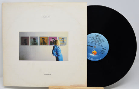 Vinyl record with cover featuring a person looking at album artwork