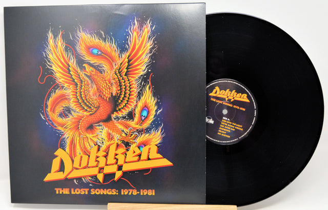 A vinyl record and its album cover for Dokken's 'The Lost Songs: 1978-1981'. The cover features a vibrant orange and yellow phoenix illustration on a dark background, with the band's name in a bold yellow font.