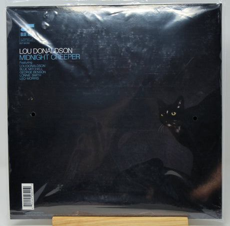 Lou Donaldson's 'Midnight Creeper' vinyl record album cover, sealed in its original plastic shrink-wrap and displayed on a wooden stand against a neutral gray background.