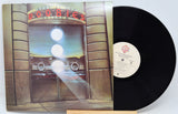 A vinyl record of The Doobie Brothers - Best Of Vol 2 with a sleeve featuring a neon-lit storefront and the band's name.