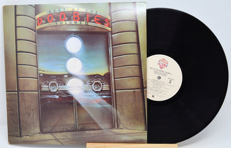 A vinyl record of The Doobie Brothers - Best Of Vol 2 with a sleeve featuring a neon-lit storefront and the band's name.