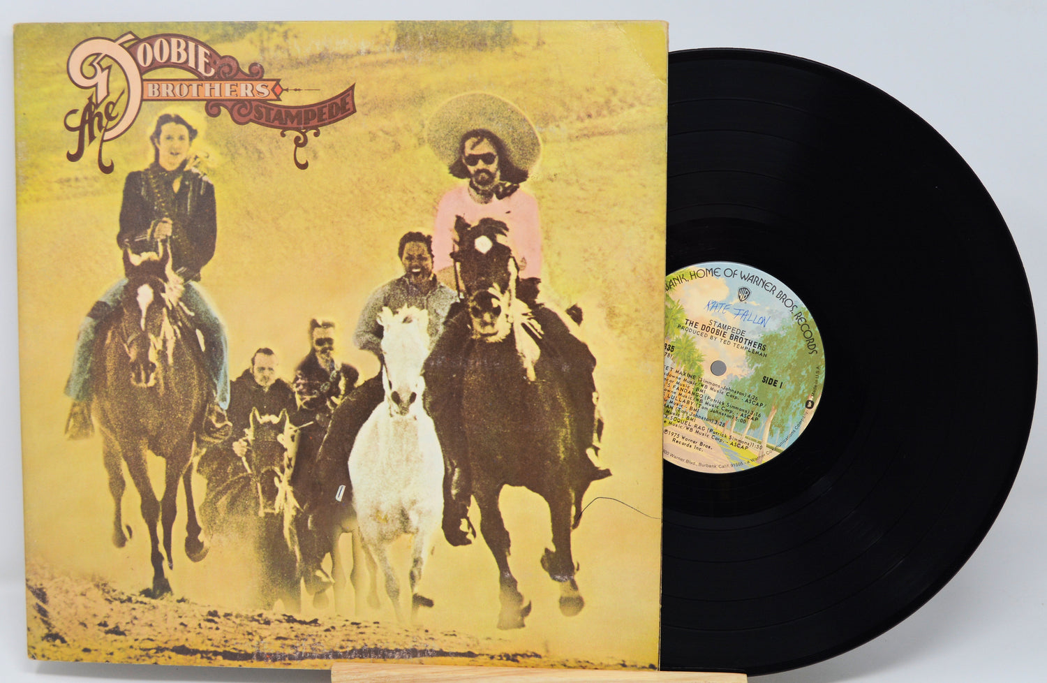 Vinyl record with a yellow cover featuring people on horseback, including a prominent image of a woman in a pink dress.