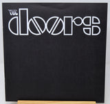The Doors 'Rumours' vinyl record album cover, featuring the band's name in white stylized lettering on a black background, displayed on a wooden stand.