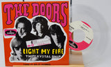 The Doors 'Light My Fire' vinyl record album with the orange cover jacket, a clear translucent record, and a pink-and-white center label on a light background.