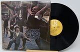 Vinyl record with a colorful cover featuring people on a street scene.