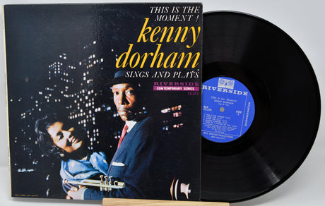 Vinyl record with cover featuring a musician and cityscape, labeled 'This is the Moment! Kenny Dorham Sings and Plays'.