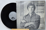 Vinyl record with cover featuring a person and text on a light gray background