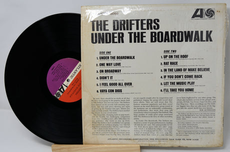 Vinyl record with cover titled 'Under the Boardwalk' by The Drifters on a light gray background.