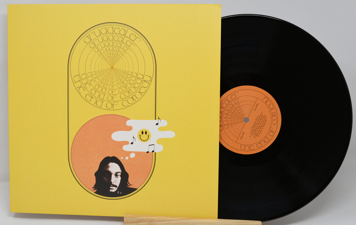 Vinyl record with yellow cover featuring a face illustration and abstract design.
