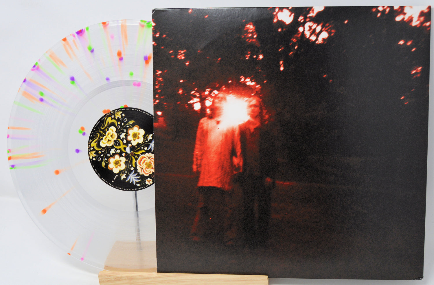 Vinyl record with a cover featuring two people under a tree, surrounded by flowers.