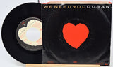 Vinyl record with a red heart on the cover and a white label on a stand.