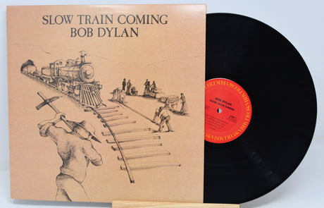 Vinyl record album sleeve for Bob Dylan's album 'Slow Train Coming' with a graphic of a train and figures on the front.