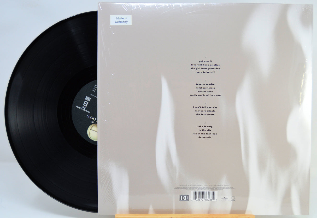 A vinyl record partially pulled from its sleeve, showing the back of the album packaging with printed track listing and barcode on a white background.
