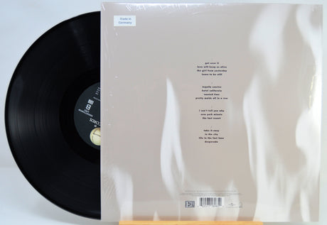 A vinyl record partially pulled from its sleeve, showing the back of the album packaging with printed track listing and barcode on a white background.