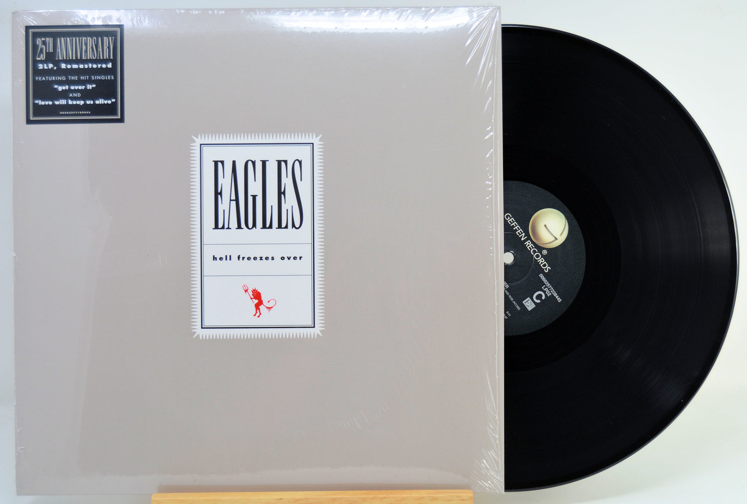 A vinyl record partially pulled from its illustrated album cover, photographed on a plain light background. 
