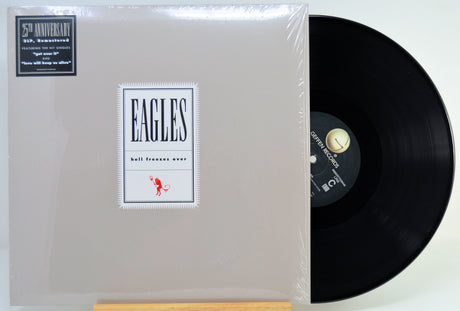 A vinyl record partially pulled from its illustrated album cover, photographed on a plain light background. 