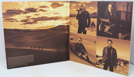 An open printed booklet or album cover spread photographed on a white surface. The pages show desert landscape photography and several sepia-toned portrait photos of a man in a dark jacket, with small text blocks along the bottom of the left page.