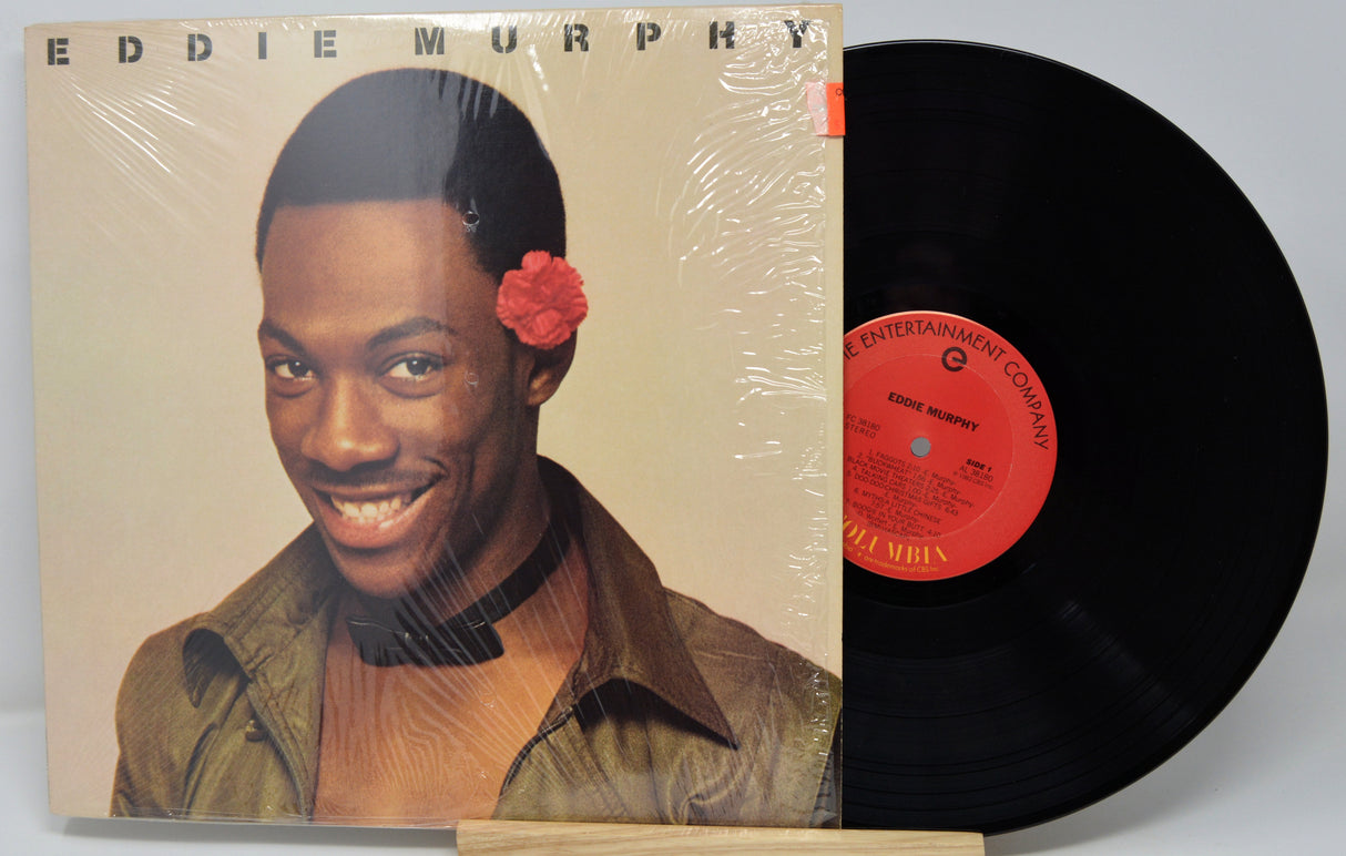 Vinyl record with cover featuring a smiling man with a flower in his hair, on a beige background.