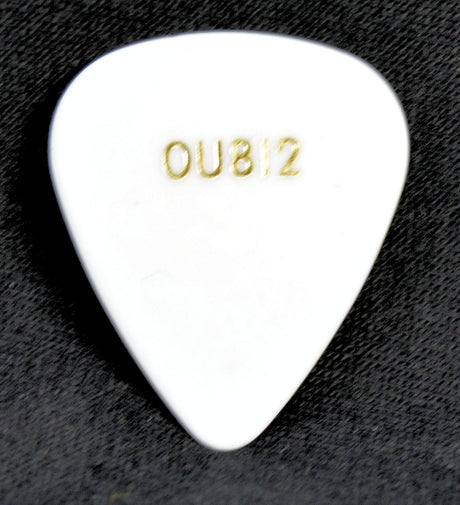 White guitar pick with 'OU812' engraving on a dark textured background