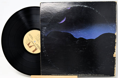 Vinyl record with a space-themed cover featuring planets and mountains.