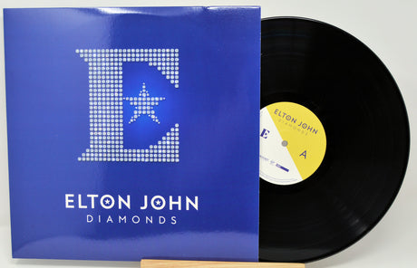 Front cover of Elton John Diamonds vinyl LP with sparkling 'E' and disc partially visible