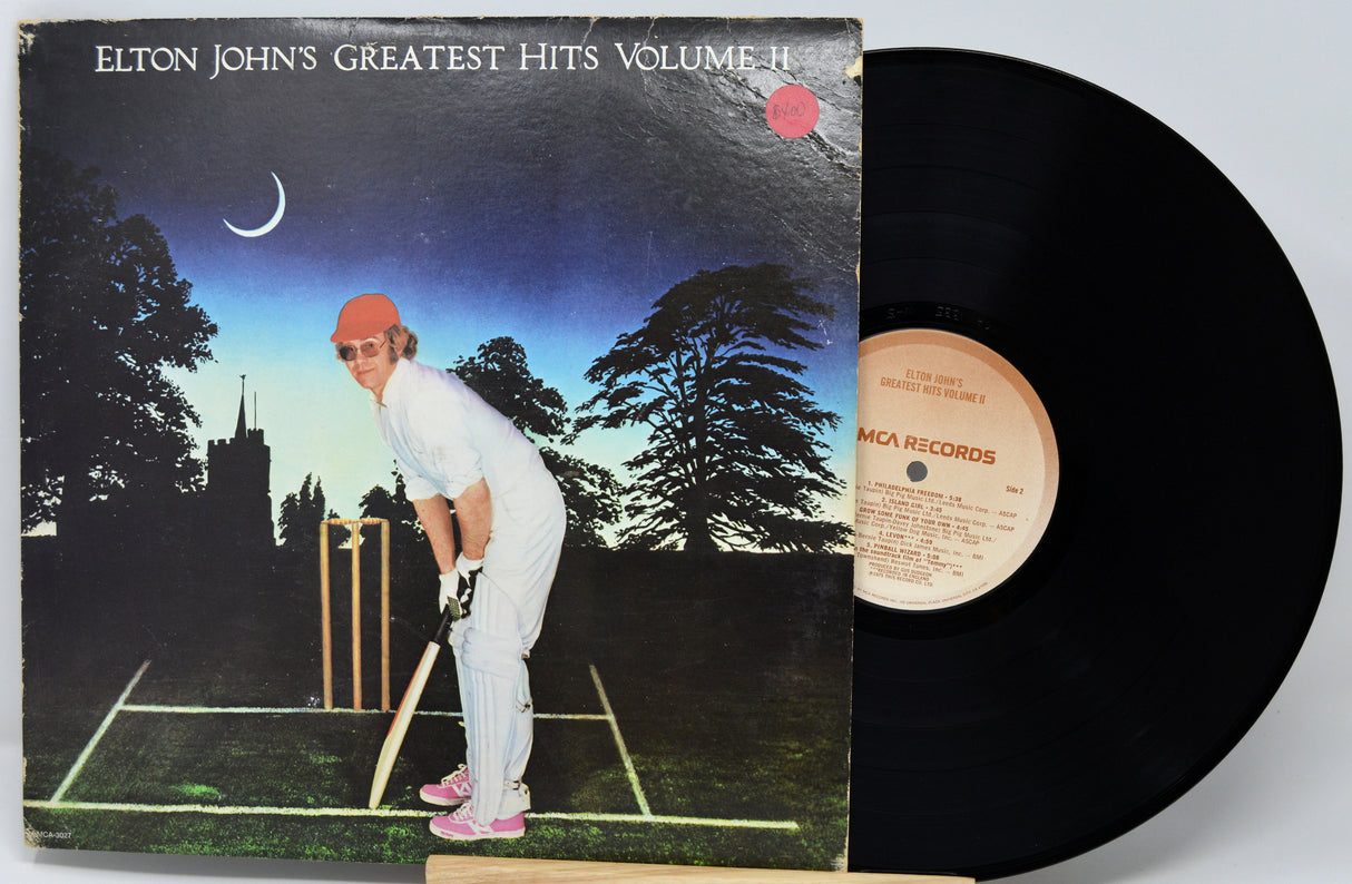Vinyl record with cover featuring Elton John playing cricket, on a white background