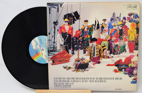 Vinyl record with a colorful album cover featuring people and objects.