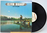 Vinyl record with cover featuring a person on a dock by a lake, titled 'Let It Flow' by Elvin Bishop.