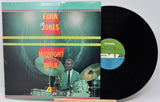 Elvin Jones 'Midnight Walk' vinyl record album with the illustrated outer cover partially pulled open to reveal the black LP disc and green/blue center label.