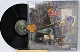 Vinyl record with a colorful cover featuring text and images on a light gray background