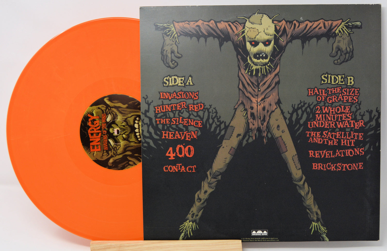 Back cover and bright orange vinyl of Energy Invasions of the Mind with scarecrow illustration