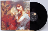 Vinyl record with a colorful cover featuring a woman's portrait and a red flower.