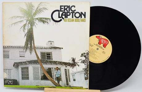 Vinyl record with cover featuring a house and palm tree, labeled 'Eric Clapton 461 Ocean Boulevard'.