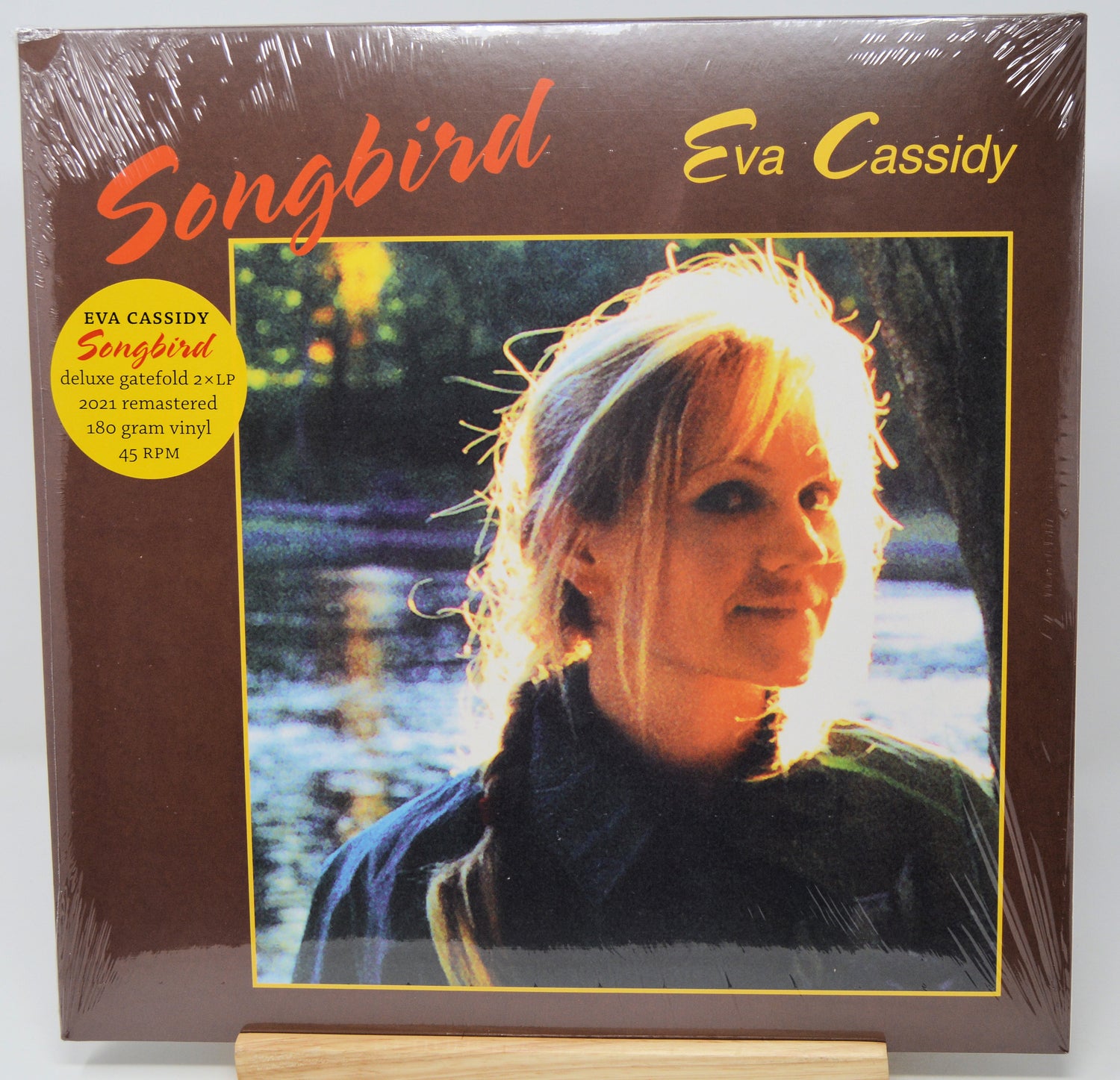 Eva Cassidy 'Songbird' deluxe gatefold vinyl LP cover, sealed in plastic shrink wrap and displayed on a wooden stand against a white background.