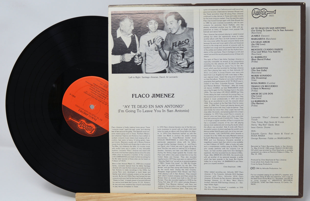 Vinyl record with a black label and a record cover featuring text and a photo of people.