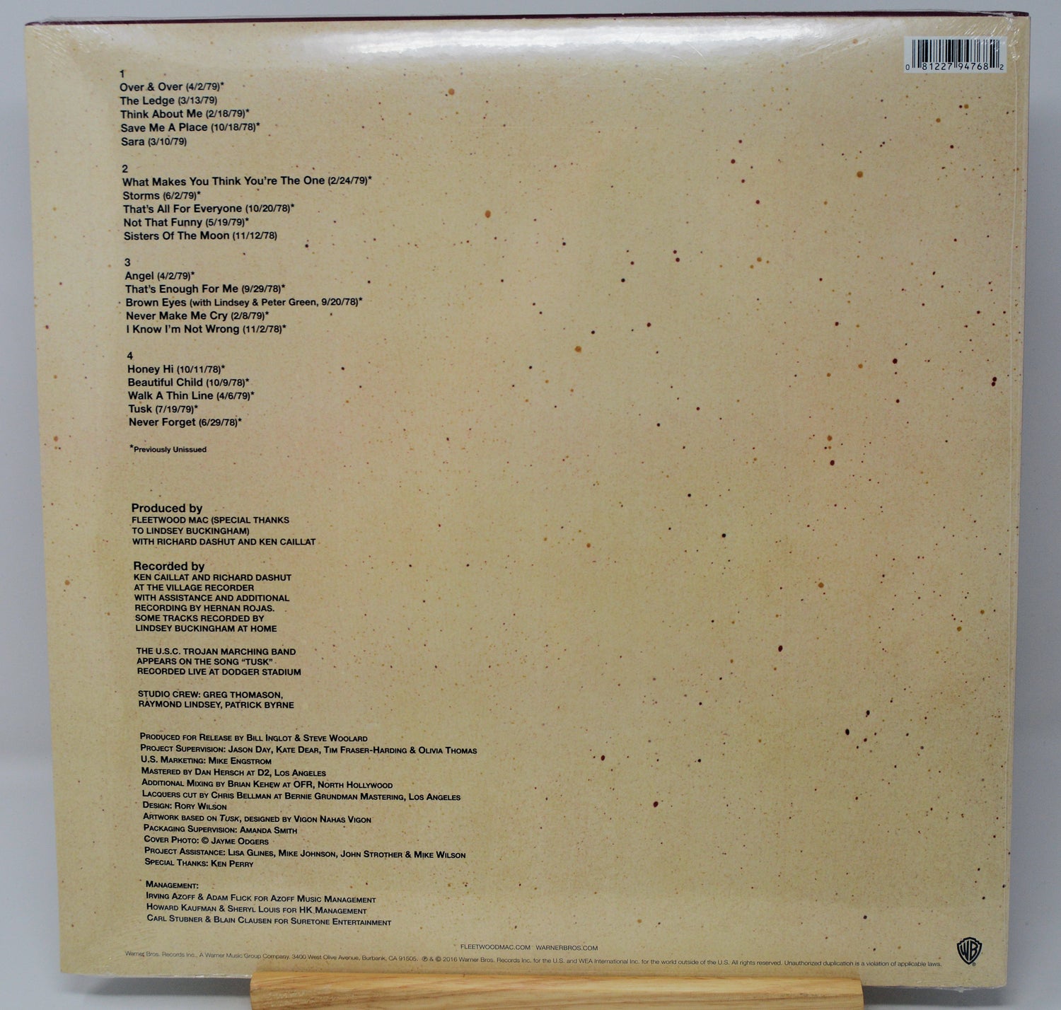 The back cover of a vinyl record sleeve, showing the tracklist, production credits, and barcode on a beige background with small dark speckles.